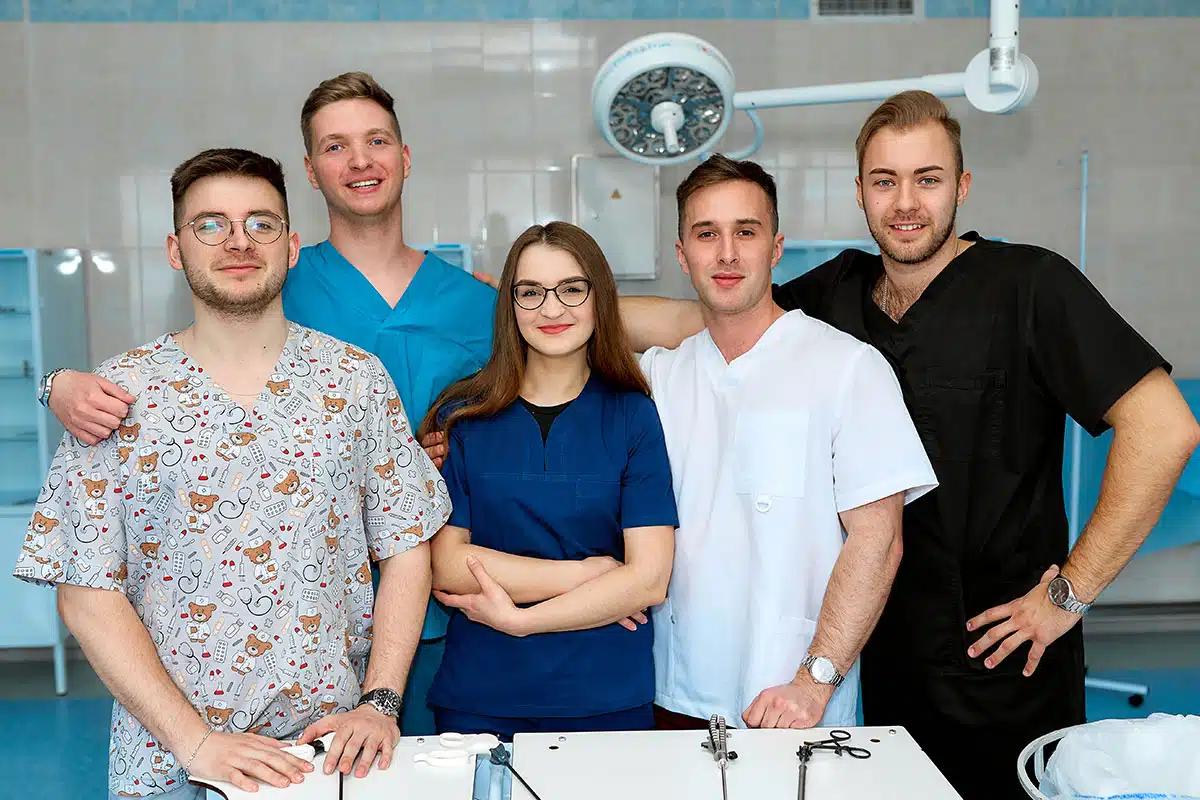 A team of young, diverse medical professionals standing confidently in a clinical setting, showcasing the Target Audiences of patients seeking reliable, relatable, and skilled healthcare providers.